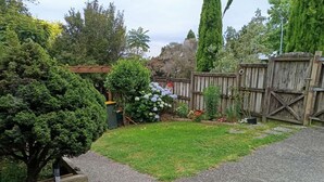 A backyard with a gravel path, a small lawn, and a wooden fence. - Cosy and Budget room in a vintage house located at Northshore, Auckland (Auckland)
