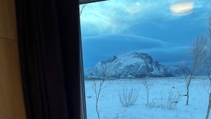 Une pièce avec une fenêtre donnant sur un paysage enneigé et des montagnes.