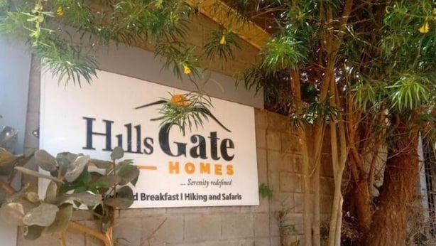Schild für 'Hulls Gate Homes' mit dem Slogan 'Gelassenheit neu definiert' und der Erwähnung von 'Frühstück, Wandern und Safari'.
