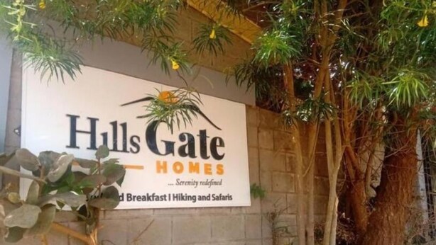 Une enseigne pour « Hulls Gate Homes » avec le slogan « Le summum de la tranquillité » et les mentions « Petit-déjeuner, randonnée et safari ».