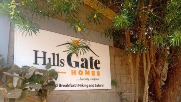 Een bord voor 'Hulls Gate Homes' met de slogan 'Sereniteit heruitgedacht' en vermeldingen van 'Ontbijt, Wandelen en Safari'.