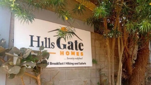 Une enseigne pour « Hulls Gate Homes » avec le slogan « Le summum de la tranquillité » et les mentions « Petit-déjeuner, randonnée et safari ».