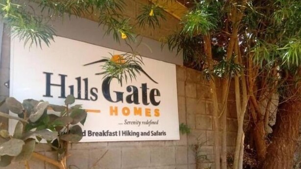 Une enseigne pour « Hulls Gate Homes » avec le slogan « Le summum de la tranquillité » et les mentions « Petit-déjeuner, randonnée et safari ».