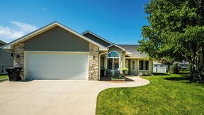 A residential house with a garage, a stone facade, and a well-maintained lawn.