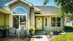 A house with a number 1690 on the side, a front porch with two chairs, and a small garden area.