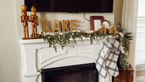 En öppen spis med en tv ovanför, träfigurer formade som nötknäckare och ordet ”LAKE” skrivet på listen ovanför spisen.