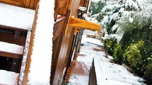 Un edificio in legno con un cartello con il numero 5, scalini coperti di neve e un giardino innevato.