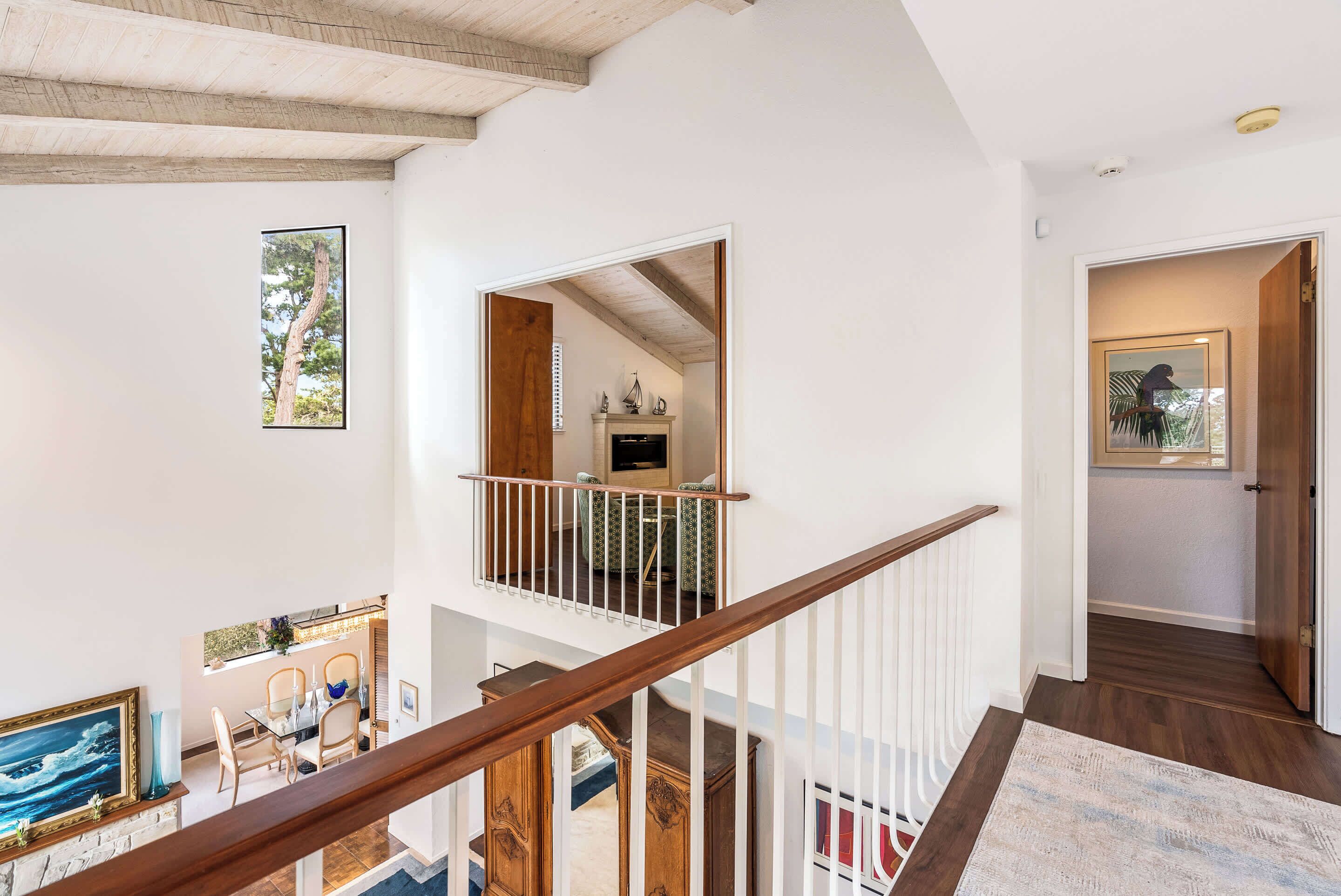 A spacious interior with a wooden staircase, a dining area, and a view of the outdoors.