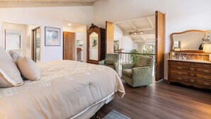 Un dormitorio amplio con una cama grande, un aparador de madera y un sillón verde.