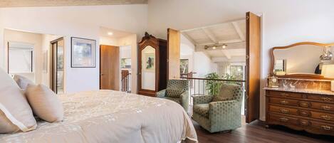 A spacious bedroom with a large bed, a wooden dresser, and a green armchair.