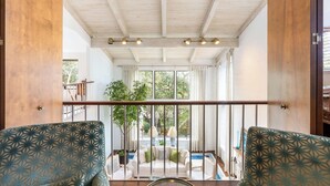 Un balcón amplio con techo de madera y vistas a una piscina y zonas verdes.