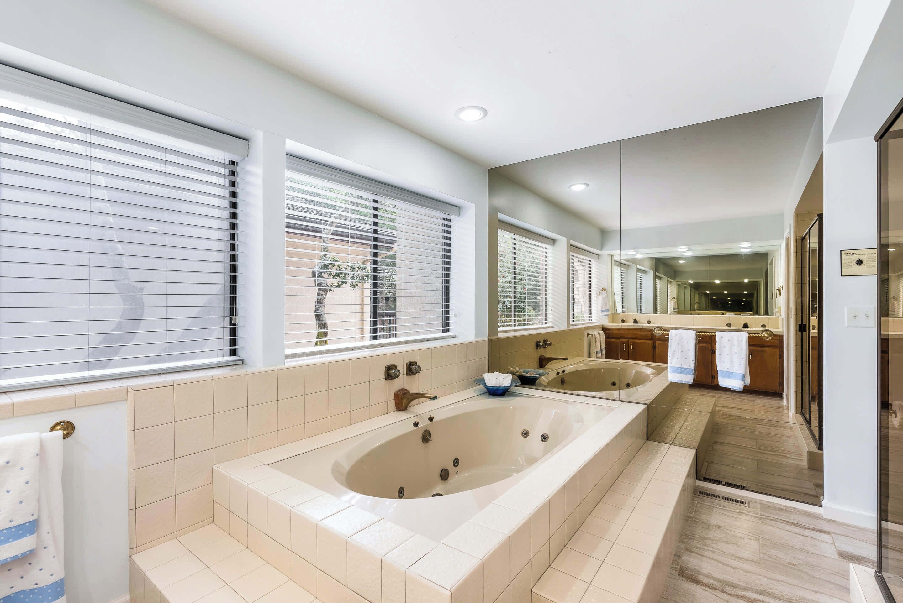 Un baño moderno con una bañera grande, una zona de ducha separada y un tocador con espejo.