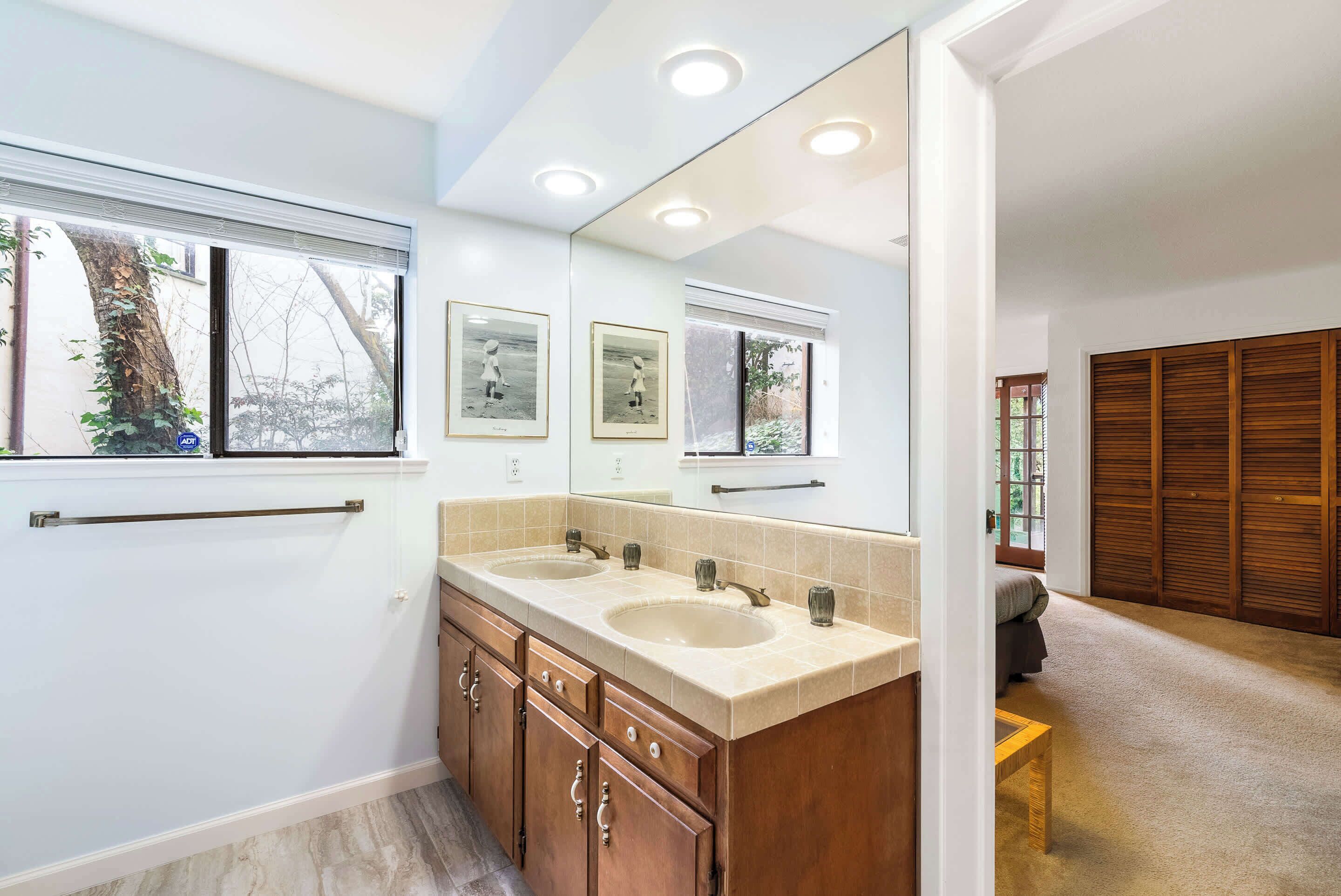A modern bathroom with two sinks, a large mirror, and a wooden vanity.
