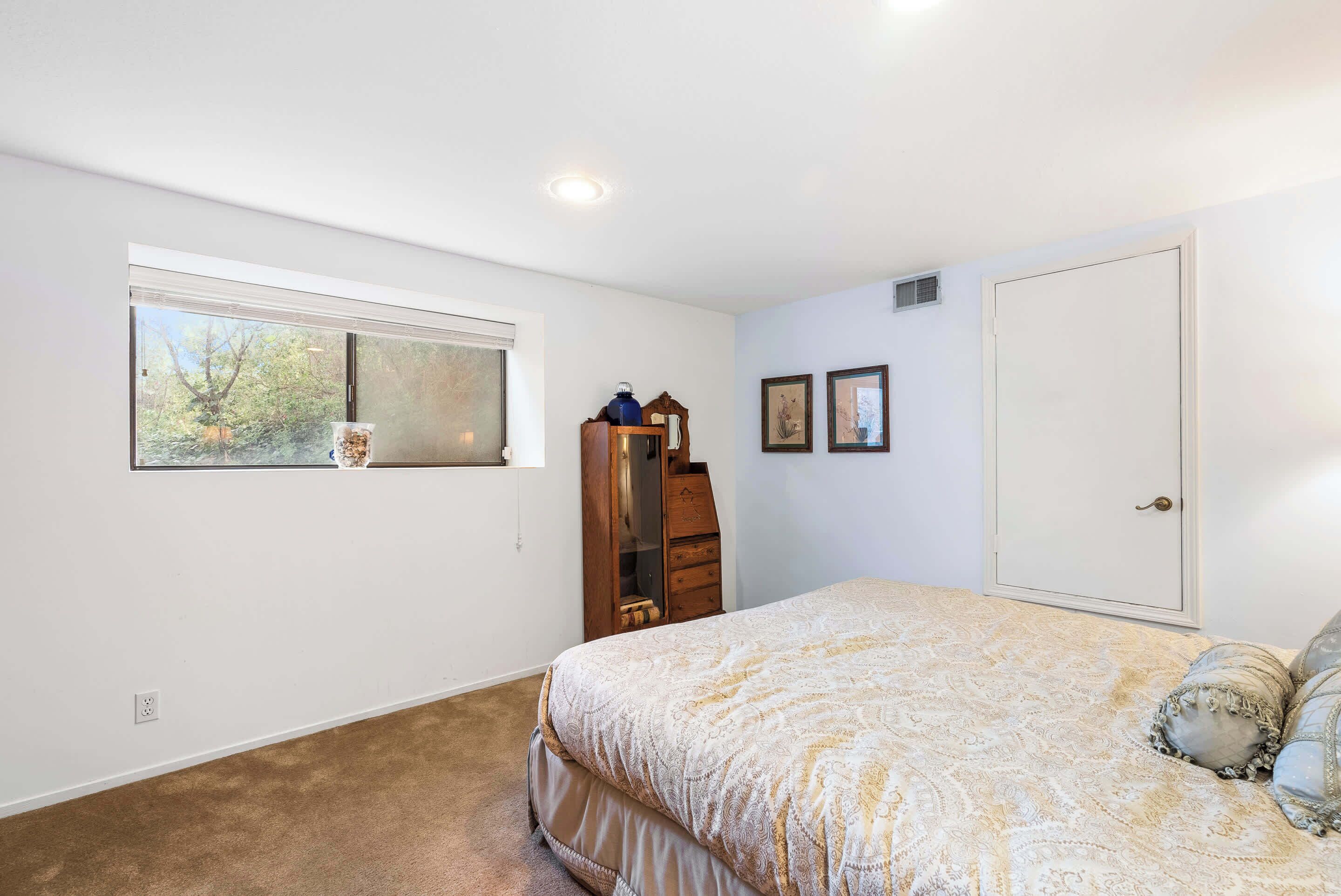 A bedroom with a bed, a dresser, a window, and a door.