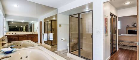 A modern bathroom with a large bathtub, a glass-enclosed shower, and a vanity with a mirror.