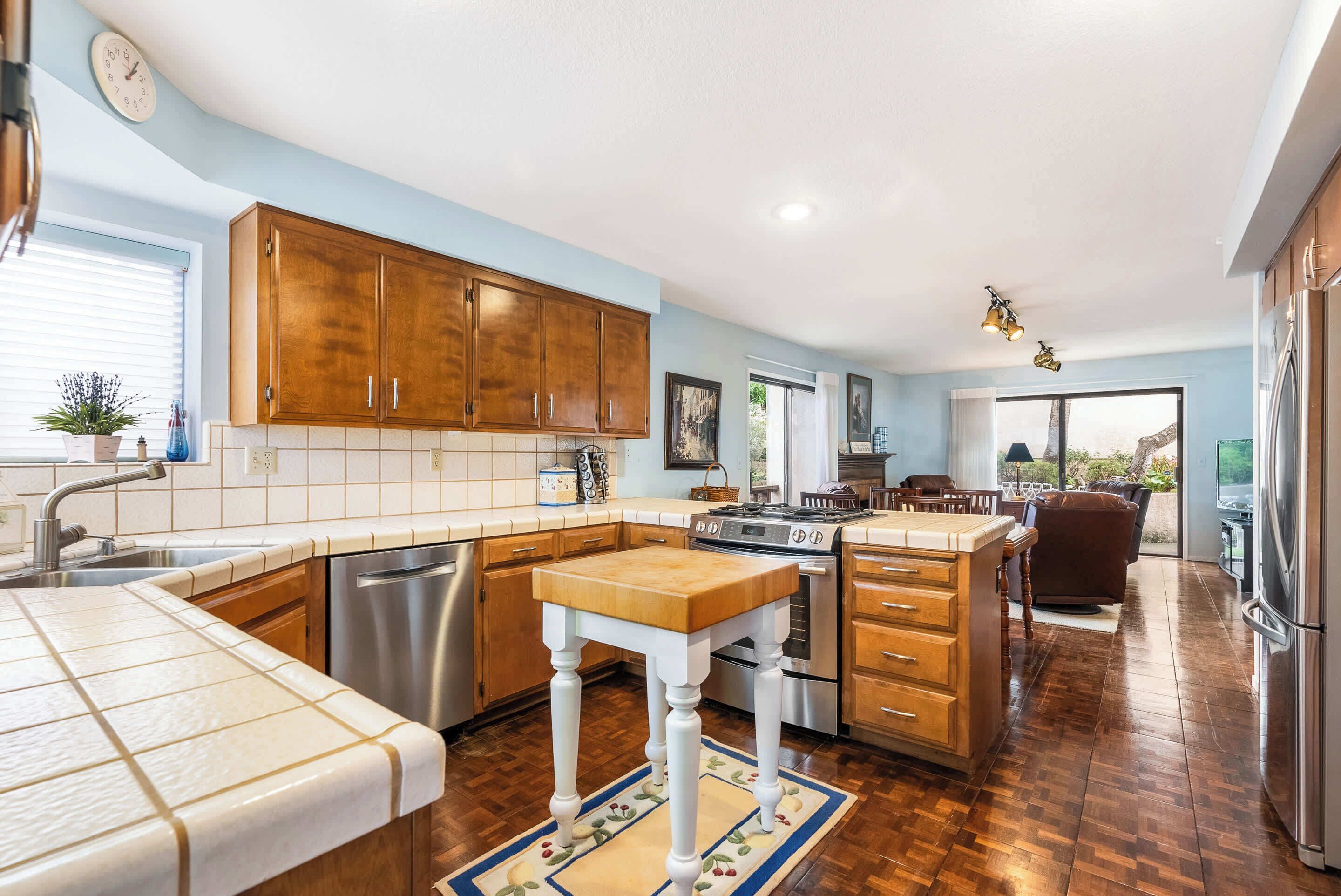A kitchen with wooden cabinets, a dishwasher, a stove, and a dining area with a table and chairs.