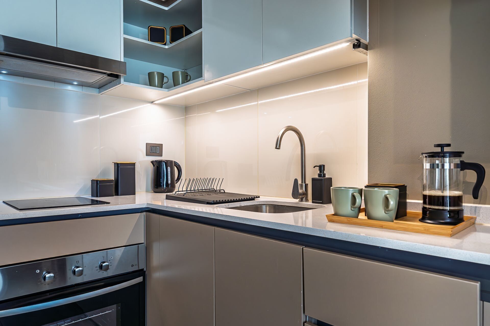 Una cocina moderna con estufa integrada, un lavamanos y una cafetera.
