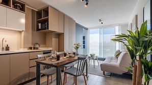 A modern kitchen with a dining area, a sofa, and a large window. - Santa Elvira Apartments (Santiago)