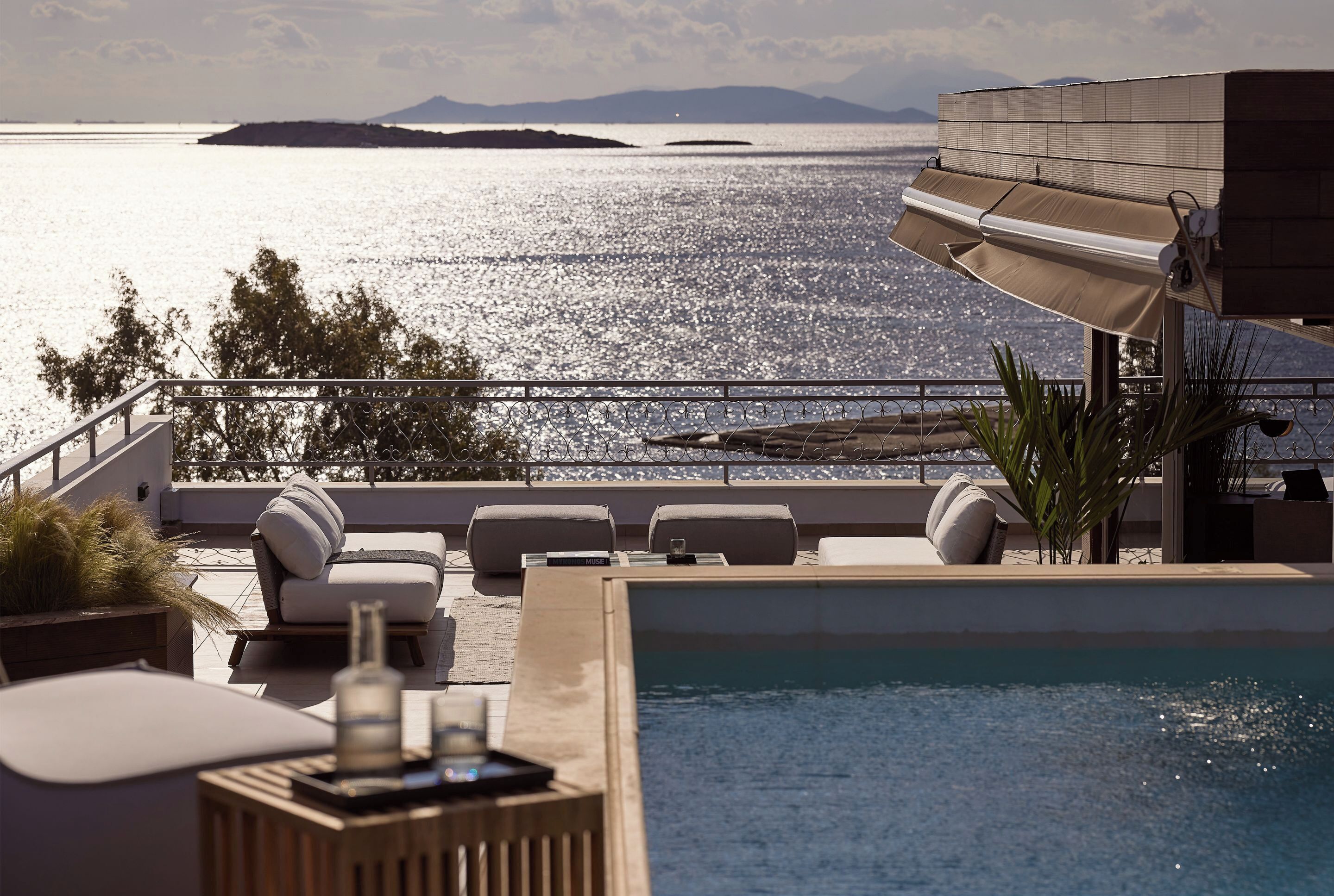 A rooftop pool area with lounge chairs, a small pool, and a view of the sea.