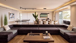 A modern living room with a sectional sofa, a coffee table, and a dining area with chairs and a table.