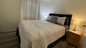 A bedroom with a bed, a nightstand, and a lamp. - Superb Chambray 4 Beds, 2 Baths in Moreno Valley, CA. (Moreno Valley)