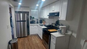 A modern kitchen with white cabinets, stainless steel appliances, and a wooden floor. - Superb Chambray 4 Beds, 2 Baths in Moreno Valley, CA. (Moreno Valley)