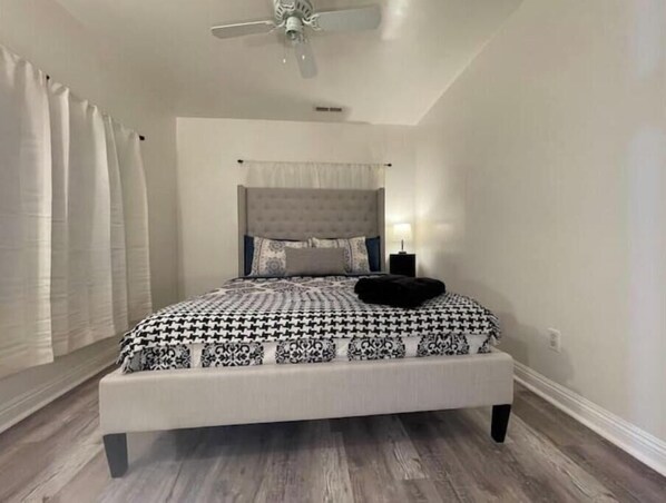 A bedroom with a bed, a ceiling fan, and a nightstand.