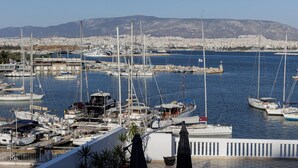 A marina with multiple boats docked, a cityscape in the background, and a clear sky. - Seaside Grey Pearl Villa 
Sea Views, Ideal for Artists & Dreamers (Pireas)
