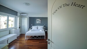 A bedroom with a bed, bedside tables, a window, and a door with the text "View Of The Heart" on it. - Seaside Grey Pearl Villa 
Sea Views, Ideal for Artists & Dreamers (Pireas)