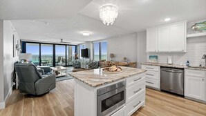 A modern kitchen with white cabinets, a marble countertop, and a built-in oven. - Book for Summer! Watercrest 709 sunset, huge balcony, beach service and towels! (Panama City Beach)