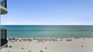 A beach with numerous umbrellas and sun loungers, a clear sky, and a calm sea. - Book for Summer! Watercrest 709 sunset, huge balcony, beach service and towels! (Panama City Beach)