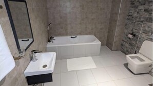 Ein Badezimmer mit einer Badewanne, einem Waschbecken, einer Toilette und einem Spiegel.