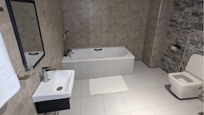 Une salle de bain avec une baignoire, un lavabo, des toilettes et un miroir.
