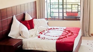 Un lit bien fait, avec une couvre-lit rouge et blanche, des oreillers blancs et une tête de lit en bois.