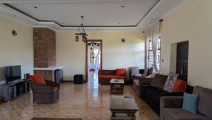 Amplia sala de estar con piso de madera en patrón de espiga, una pared de acento de ladrillo y una combinación de sofás y una mesa de centro.