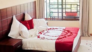 Un lit bien fait, avec une couvre-lit rouge et blanche, des oreillers blancs et une tête de lit en bois.