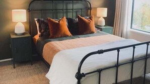A bedroom with a metal bed frame, a dark wall, and a large window. - Scandi City Escape | Walk Everywhere, Near Stadium (Christchurch)