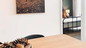 A room with a wooden dining table, a framed wildlife painting, and a basket of pinecones. - Scandi City Escape | Walk Everywhere, Near Stadium (Christchurch)