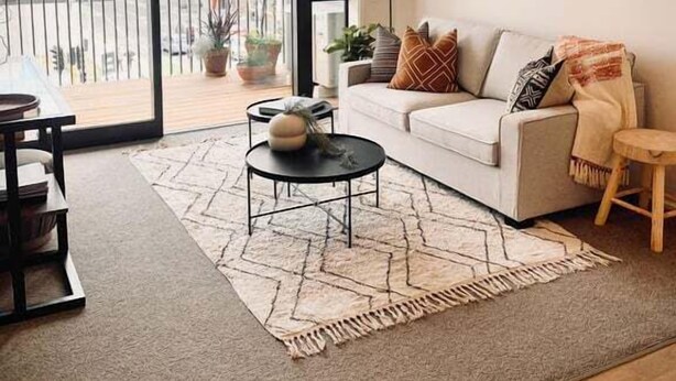 A modern living room with a sofa, a coffee table, and a view of the city through large glass doors. - Scandi City Escape | Walk Everywhere, Near Stadium (Christchurch)