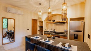 A modern kitchen with a large island, pendant lights, and a built-in refrigerator.