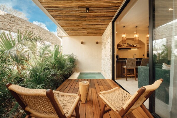 A wooden deck with two wicker chairs, a small table, and a pool.