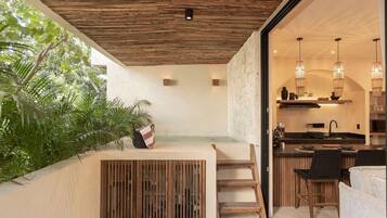 A modern kitchen with a stone wall, wooden ceiling, and a dining area with a bench and chairs.