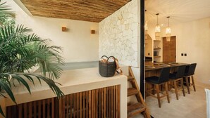 A modern kitchen with a stone backsplash, wooden ceiling, and a dining area with a large table and chairs. - Jungle Cove w private pool n concierge. 3p.  2 TVs (Tulum)