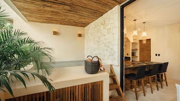 Cozinha moderna com painel de pedra, teto de madeira e área de refeições com uma mesa grande e cadeiras.