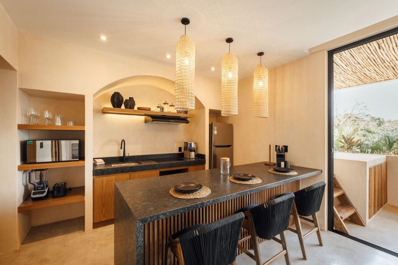 A modern kitchen with a central island, wooden cabinets, and a built-in oven. There are three pendant lights hanging above the island.