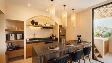 A modern kitchen with a central island, wooden cabinets, and a built-in oven. There are three pendant lights hanging above the island.