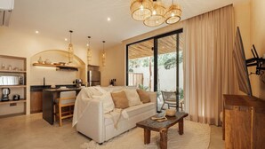 A modern living room with a sofa, coffee table, and dining area. - 1BR Hidden Gem–Priv Pool+Garden at Launch Price (Tulum)
