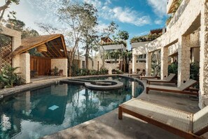 A pool area with lounge chairs and a stone building.