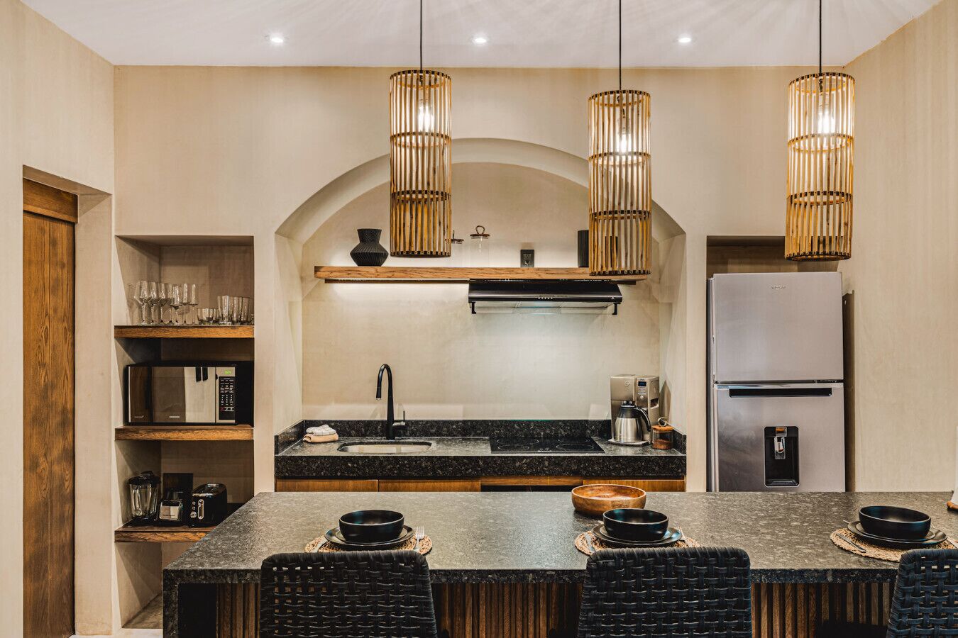 A modern kitchen with a central island, built-in appliances, and hanging pendant lights.