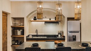 A modern kitchen with a central island, built-in appliances, and hanging pendant lights. - Jungle Luxury: 1-BR, Plunge Pool, Fully Equipped (Tulum)